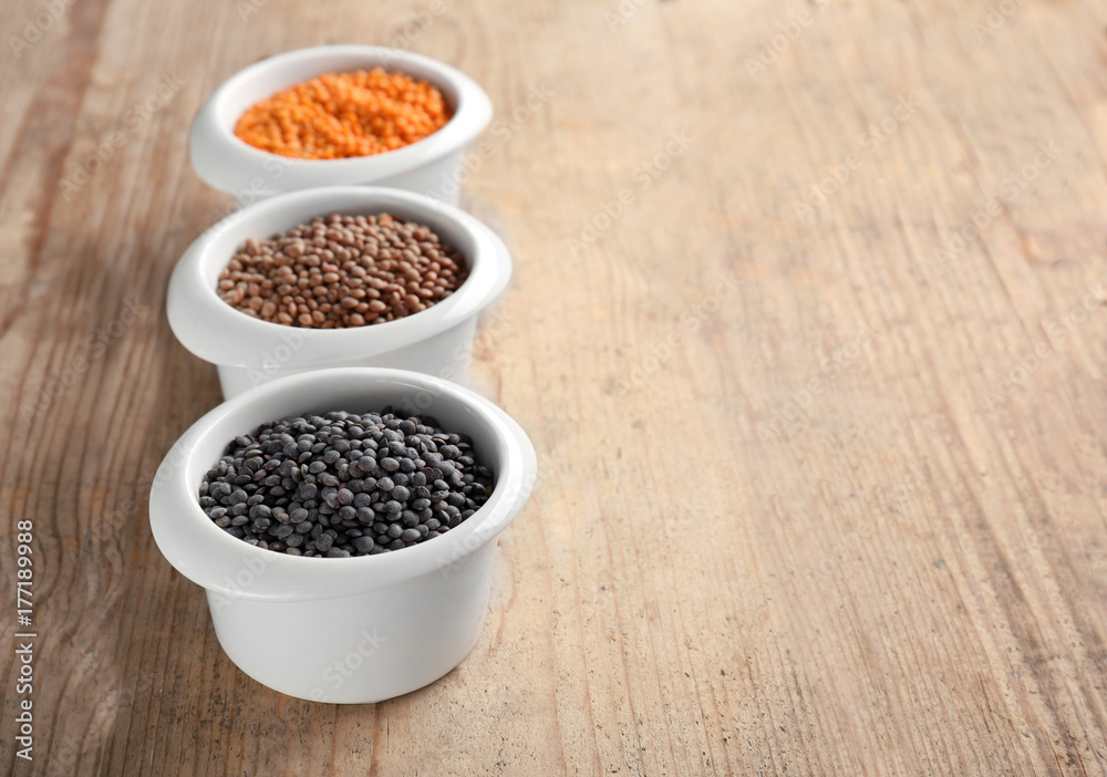 Bowls with different lentils on wooden table Bowls with different lentils on wooden table