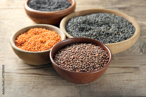 Bowls with different lentils on wooden table