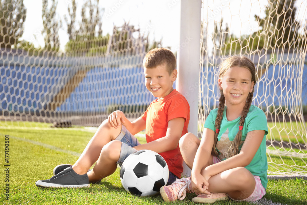 Cute children with soccer ball on field