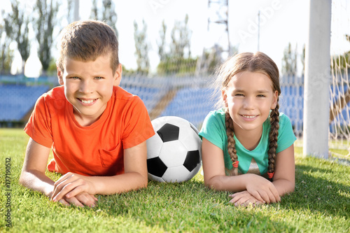 Cute children with soccer ball on field