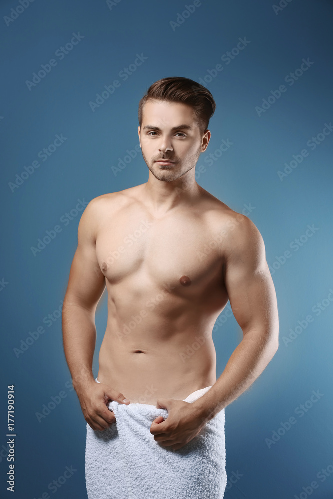 Sexy man wrapped in towel on color background