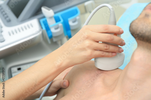 Doctor conducting ultrasound examination of patient's shoulder in clinic