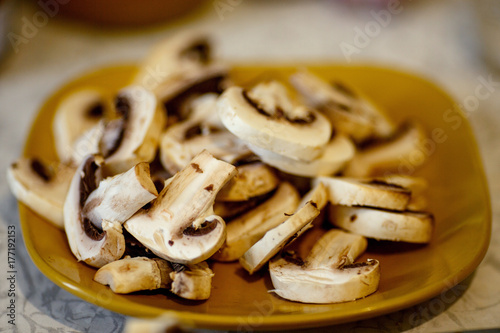 sliced Agaricus champignon mushrooms on a yellow plate