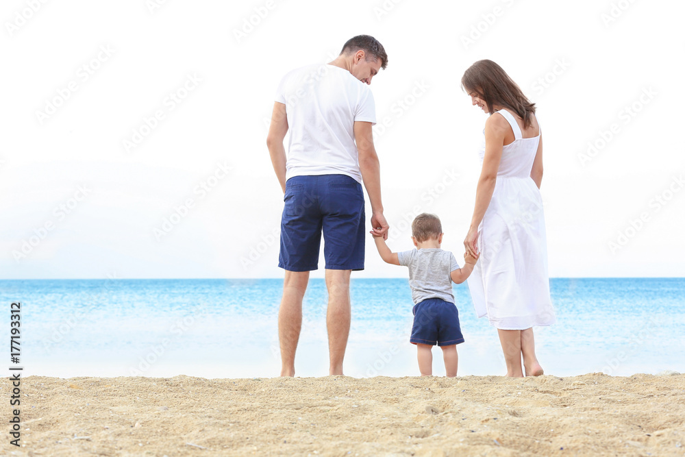 Happy couple with little son on beach