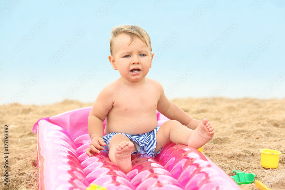 Cute baby boy sitting on inflatable mattress at beach Cute baby boy sitting on inflatable mattress at beach