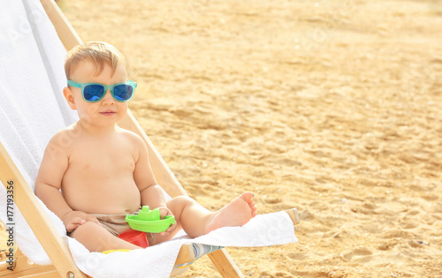 Little boy sitting on beach...