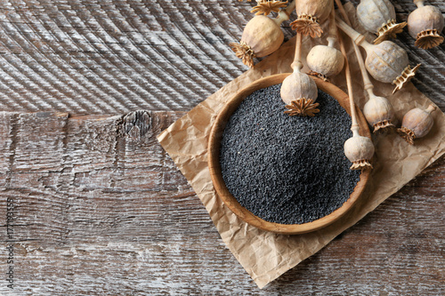 Poppy heads and plate with seeds on wooden table