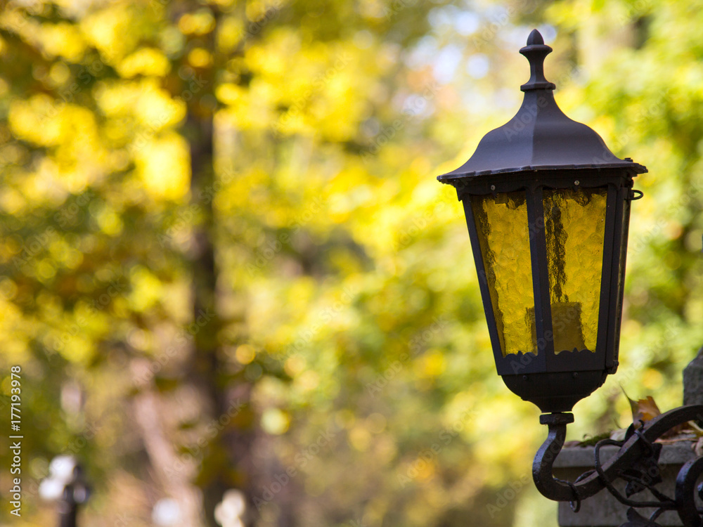 Old vintage metal lantern on autumn trees background. Shallow depth of field