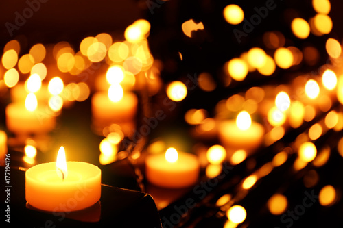 Burning candles and Christmas lights on piano  closeup