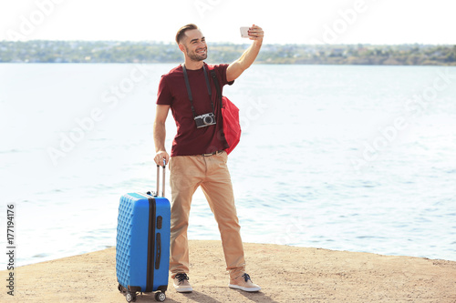 Handsome young tourist taki...