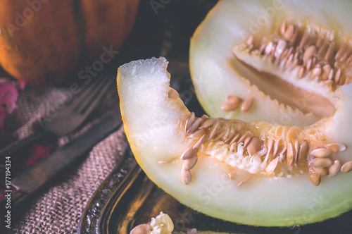 A piece of ripe yellow melon lying on a rustic table. photo