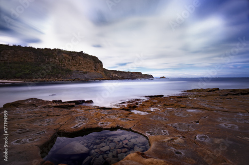 Rugged coastline with still rock pool in the foreground