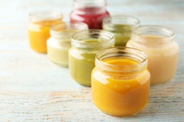 Assortment of jars with tasty baby food on wooden table