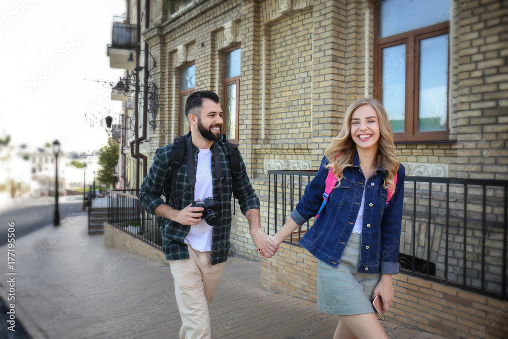 Happy young tourists walking on street in city