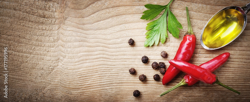 Fototapeta Naklejka Na Ścianę i Meble -  Red chili peppers, peppercorns, parsley and extra virgin olive oil on wooden background