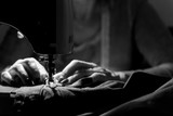 Close up on sewing machine and seamstress' hand while she is working. Black and white