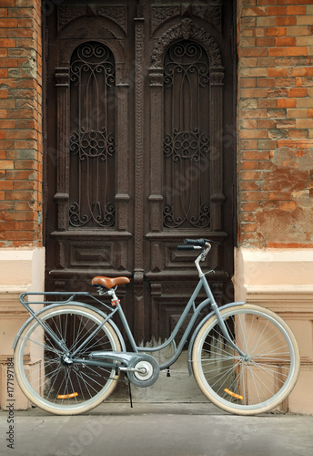Retro bicycle near house entrance on city street