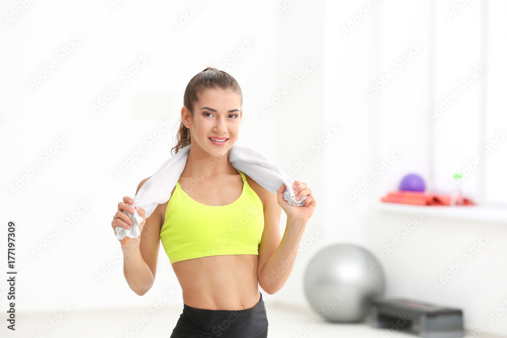 Young sporty woman with towel in gym