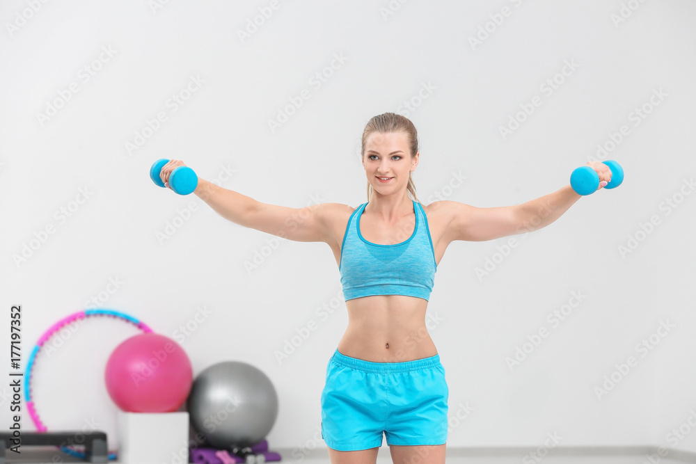 Young sporty woman training with dumbbells in gym Young sporty woman training with dumbbells in gym