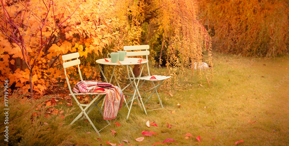 Obraz premium Colorful autumn garden nook with hot tea and blanket