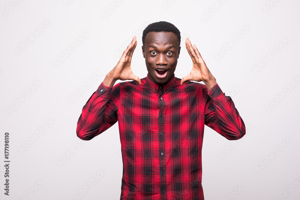 Portrait of shocked young African American man looking at the camera in surprise, stunned with some incredible story, holding hands on head. Human expressions and emotions