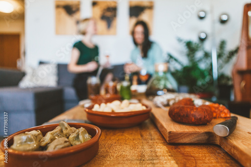 two young women are relaxing and chatting together with wine and ready to eat food 