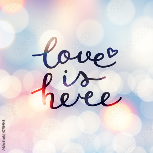 love is here lettering, vector handwritten text on blurred lights