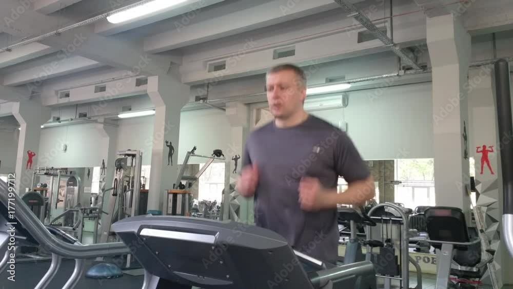 adult man age 30-40 running on a treadmill in gym to stay fit in great shape. struggling with excess weight adult man age 30-40 running on a treadmill in gym to stay fit in great shape. struggling with excess weight