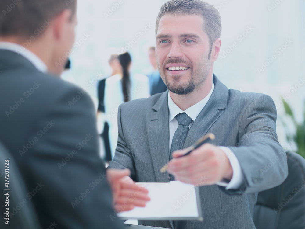 Businessman giving a pen to seal deal with his partner Businessman giving a pen to seal deal with his partner