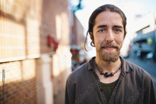 Portrait of young traveler man standing on city sidewalk