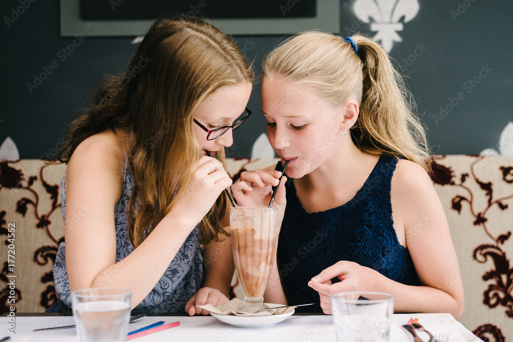sisters trying to outdrink a chocolate milkshake they are sharing sisters trying to outdrink a chocolate milkshake they are sharing