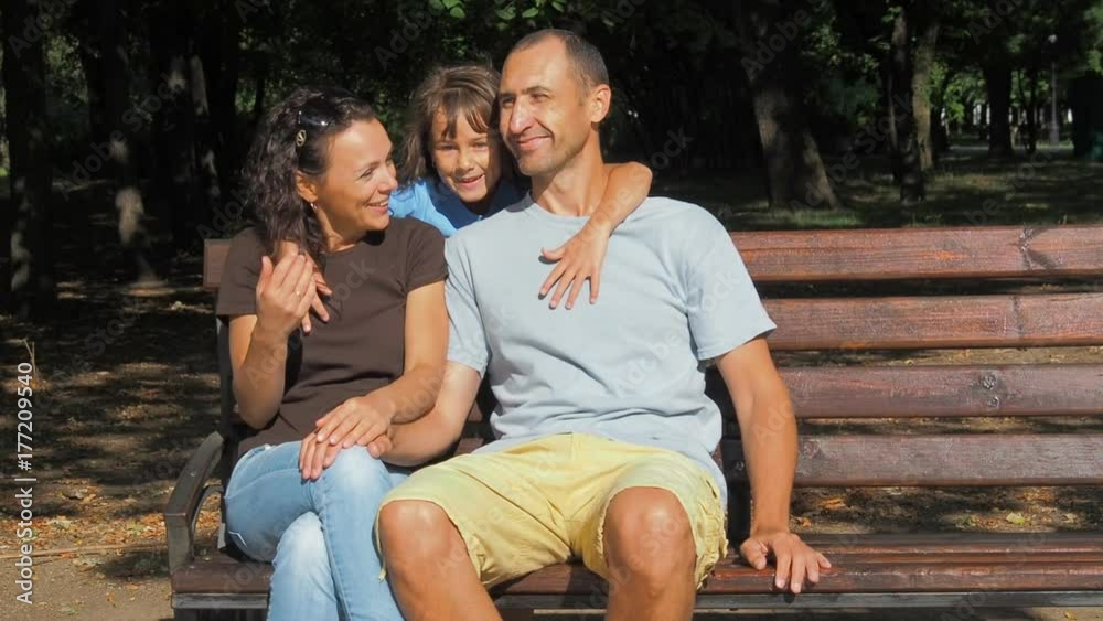 Happy family in the park. Daughters hug their parents. Happy family in the park. Daughters hug their parents.