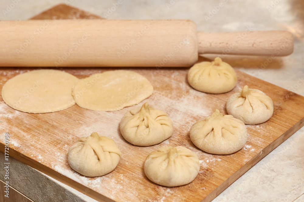 Homemade raw khinkali dumplings on wooden board