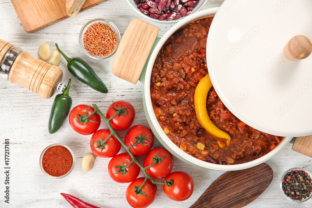 Saucepan with delicious chili con carne on table