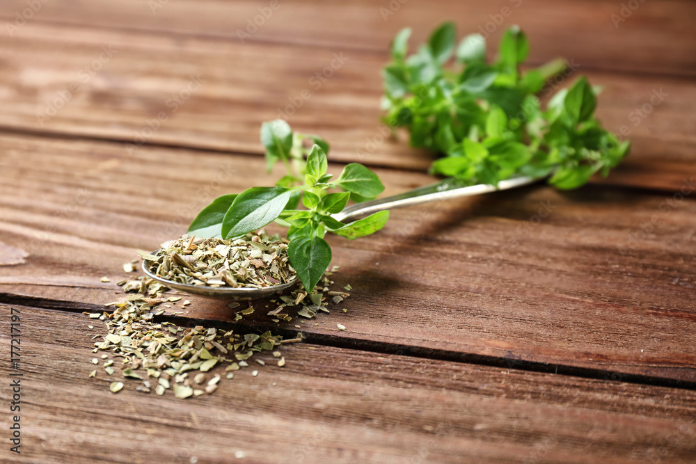 Spoon with aromatic dried oregano on wooden background Spoon with aromatic dried oregano on wooden background