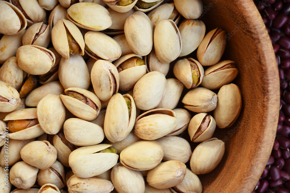 pistachios in wooden bowl on red bean background
