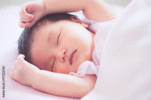 Cute asian newborn baby girl sleeping in bed with pink blanket