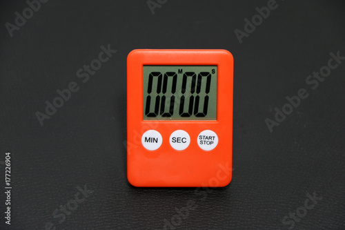 Orange stopwatch on black floor background . The number on the dial of 00:00 symbolic of start. photo