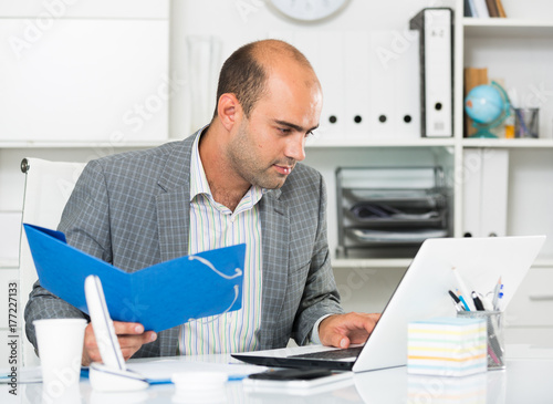 Cheerful man with folders and files at the laptop