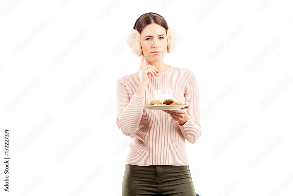 Studio portarit of young woman in earmuffs holding plate with biscuits Studio portarit of young woman in earmuffs holding plate with biscuits