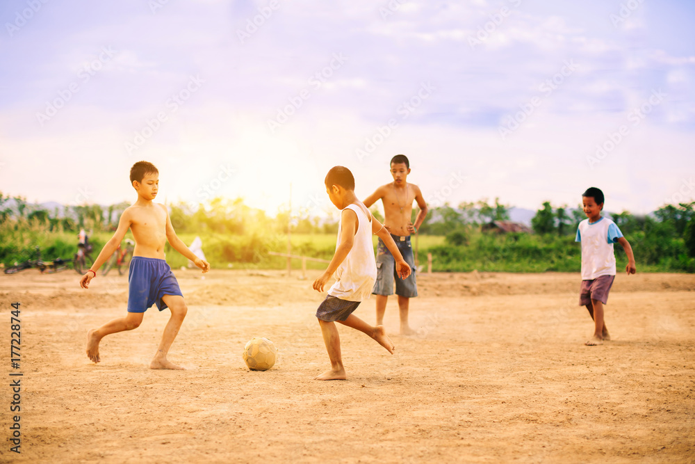 Naklejka premium An action picture of a group of kids playing soccer football for exercise in community rural area.