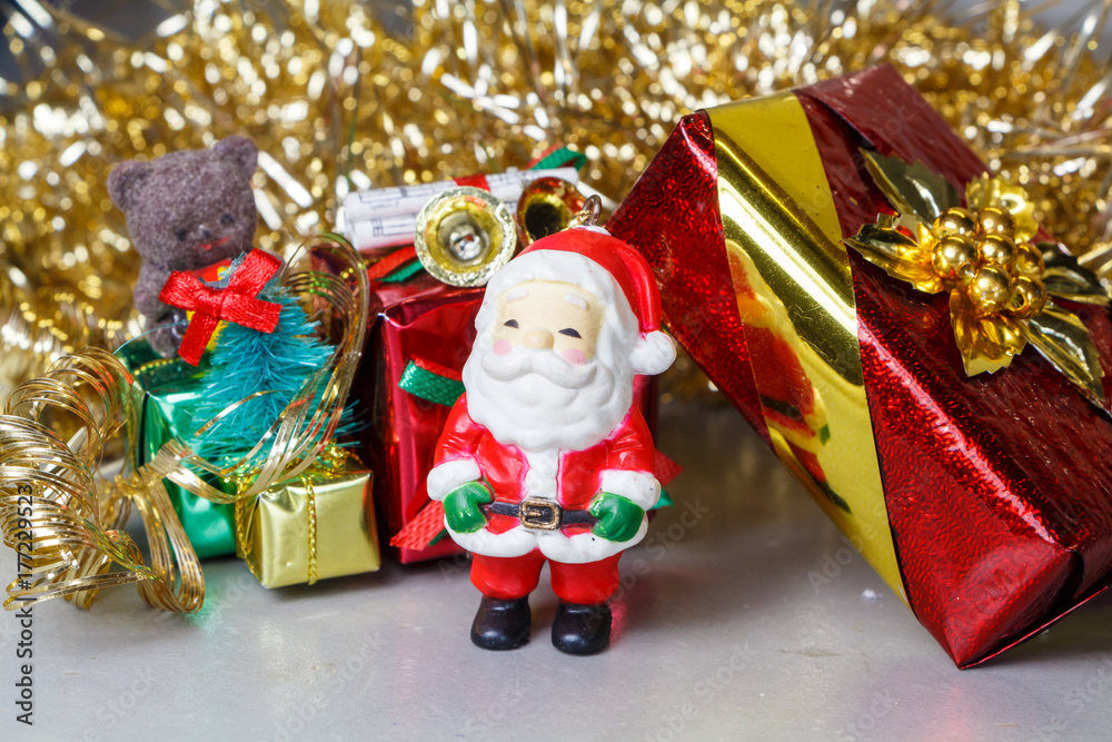 Figurine de Père Noël et paquets cadeaux devant une guirlande dorée Figurine de Père Noël et paquets cadeaux devant une guirlande dorée