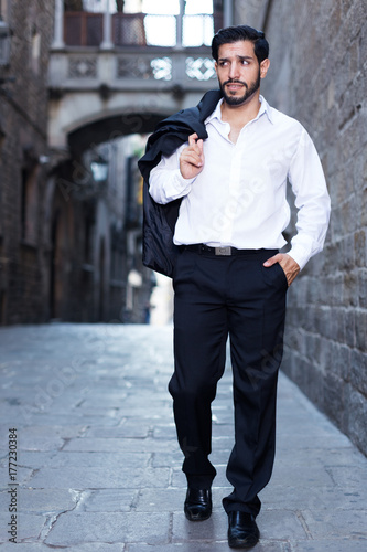 Man in formal clothes strolling past old castle