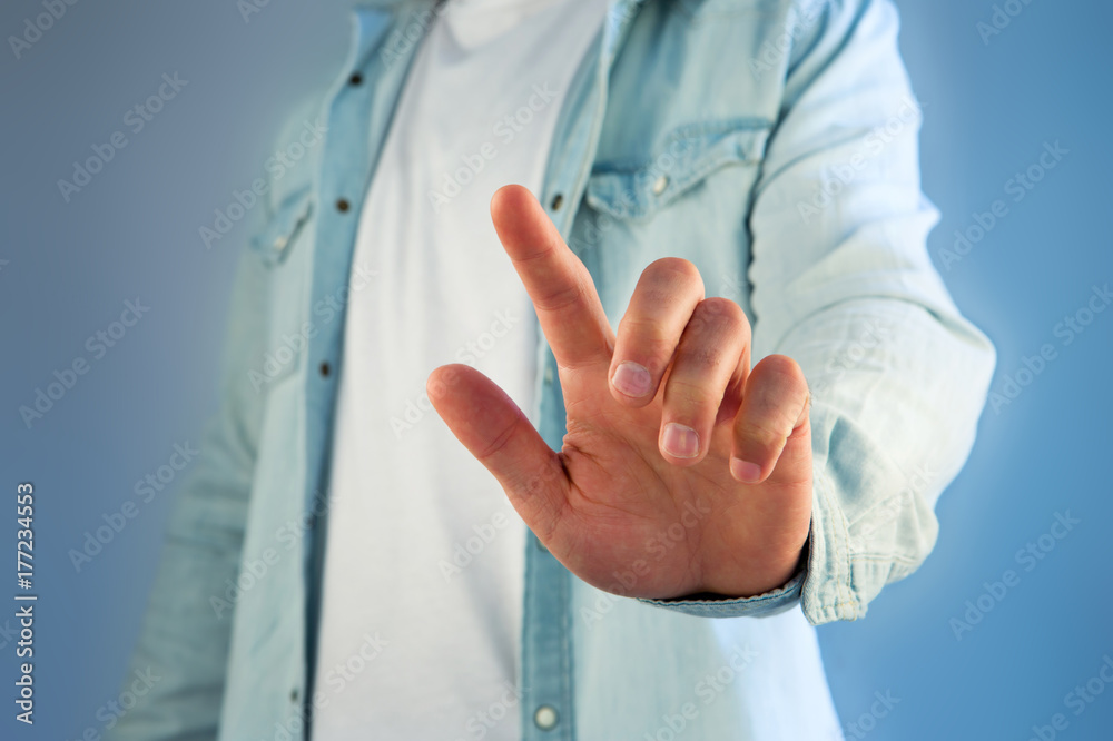 Fototapeta premium Young man touching with his finger an interface on a color background