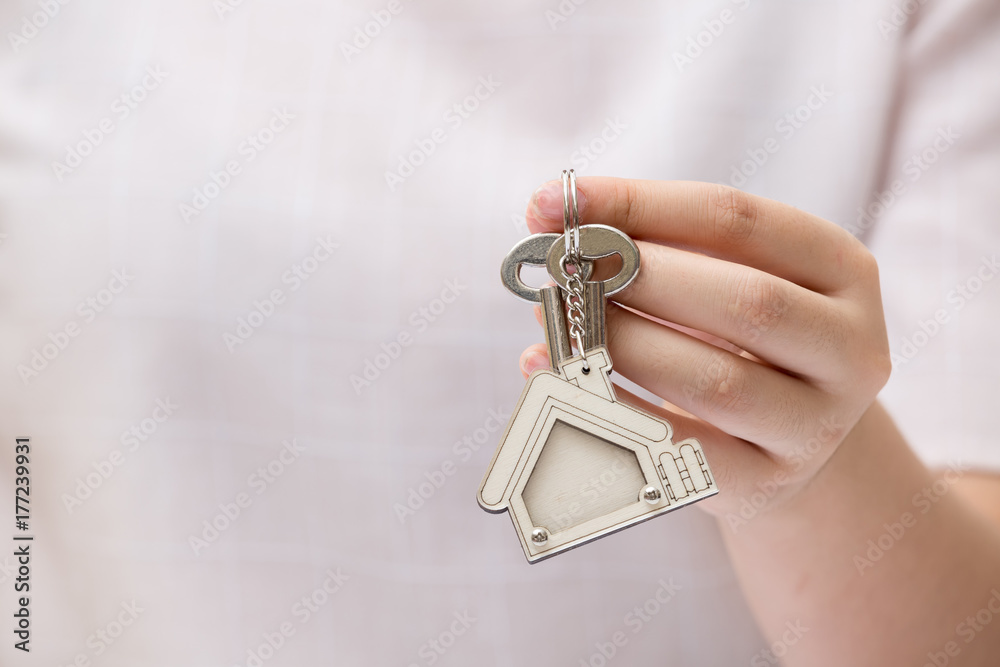 Fototapeta premium Woman hand holding home key. Concept for real estate business.