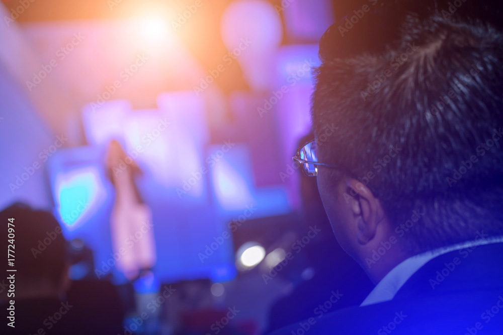 Businessman looking at the speaker giving a talk on corporate Business Conference hall or seminar room background. meeting, event, business, presentation, exhibition.