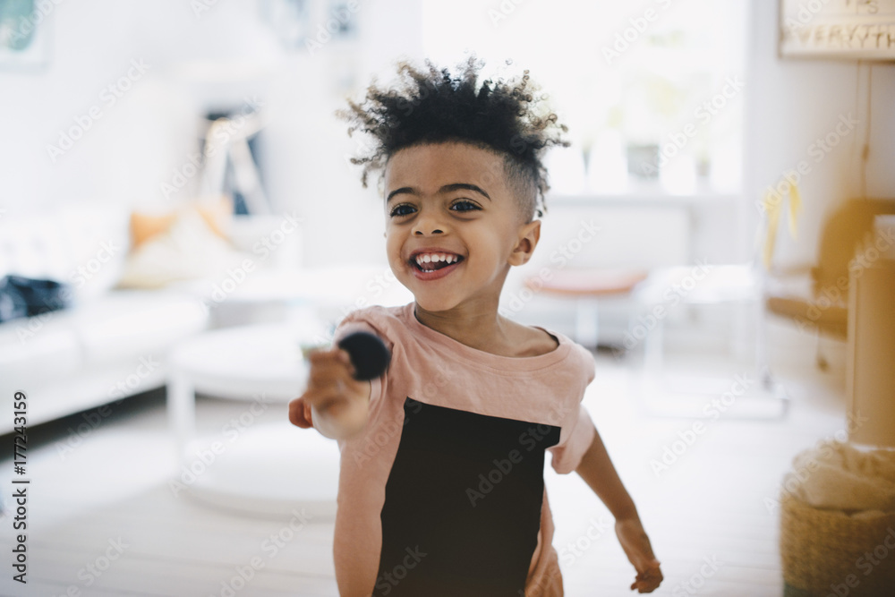 Happy boy holding toy while standing at home Happy boy holding toy while standing at home