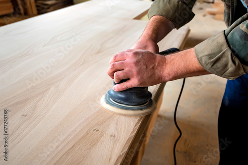 Man sanding wood with orbital sander in a workshop photo