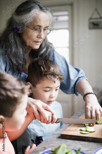 Boys heling grandmother in kitchen photo