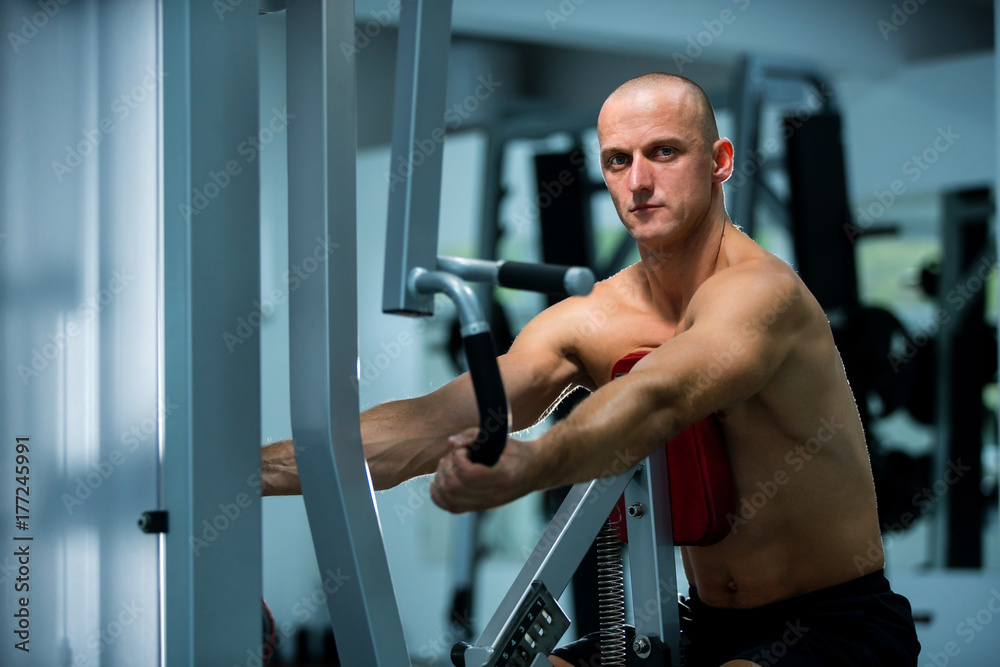 Adult muscle man using gym machines for working out